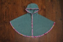 Girl's basic single layer seafoam green fleece poncho edged with pink jungle print bias binding, secures with plastic snappers under the arms. Size 0-3 months. £16 + p&p.